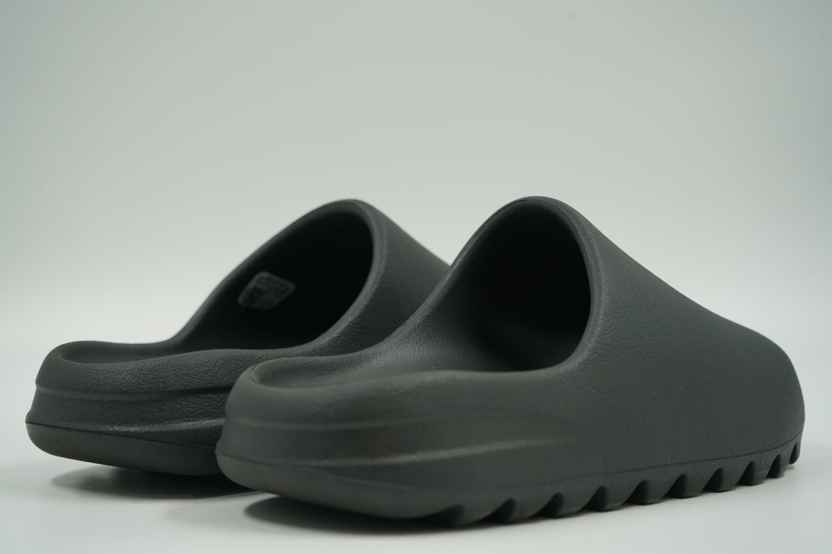 Pair of pre-owned adidas Yeezy Slides in Dark Onyx foam, back view of heels