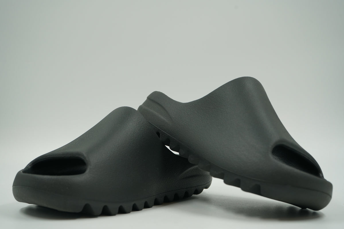 Pair of pre-owned adidas Yeezy Slides in Dark Onyx foam, stacked view of the inner sides