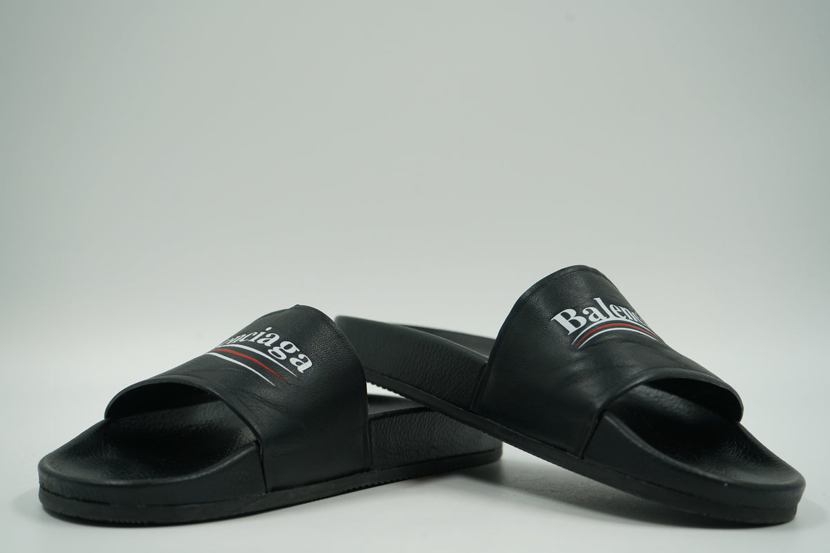 Pair of pre-owned Balenciaga pool slides in black with Political Campaign logo, stacked view of inner sides