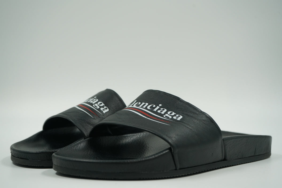 Pair of pre-owned Balenciaga pool slides in black with Political Campaign logo strap, front angle view