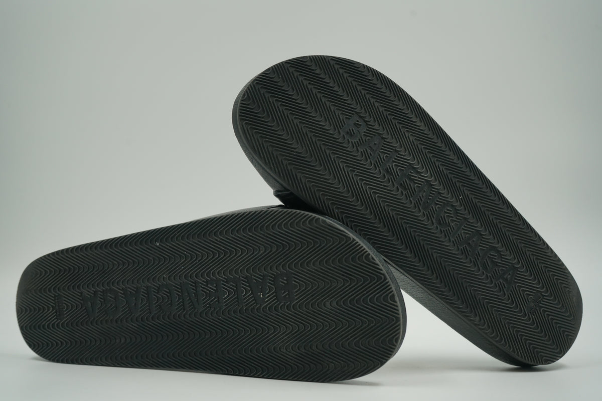 Pre-owned Balenciaga pool slides in black, outsole view with zigzag tread and embossed logo