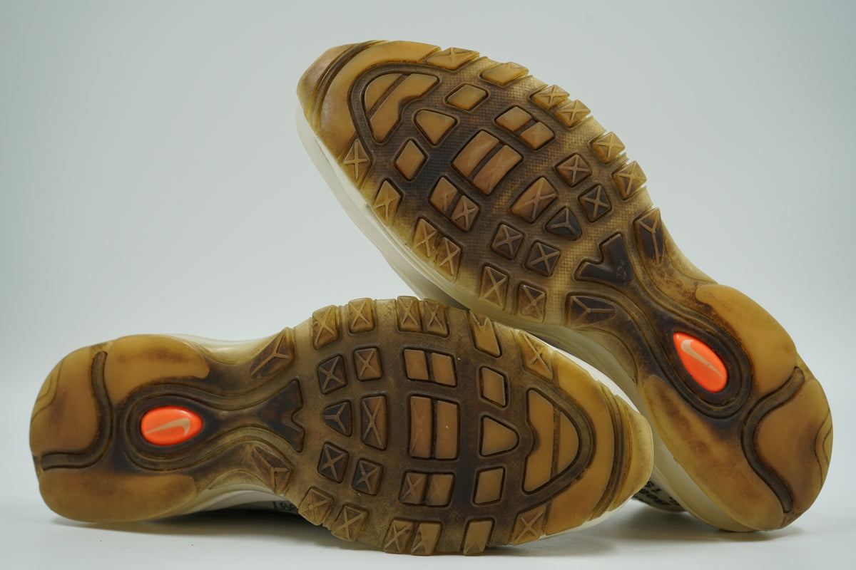 Yellowed outsoles of pre-owned Off-White x Nike Air Max 97 The Ten with orange Swoosh pods and visible wear