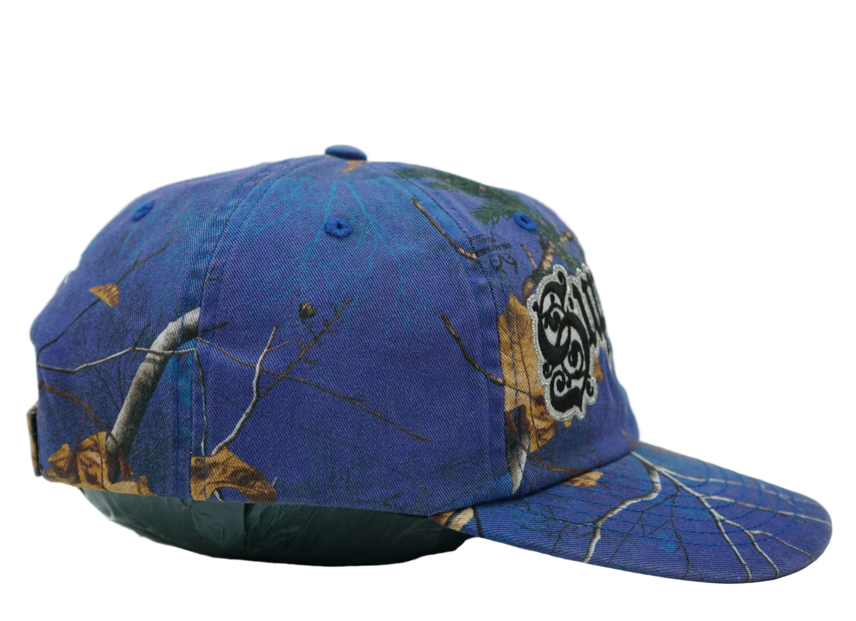 Supreme Bottle Opener 6-Panel cap in blue tree and leaf camo with gothic logo, side profile view