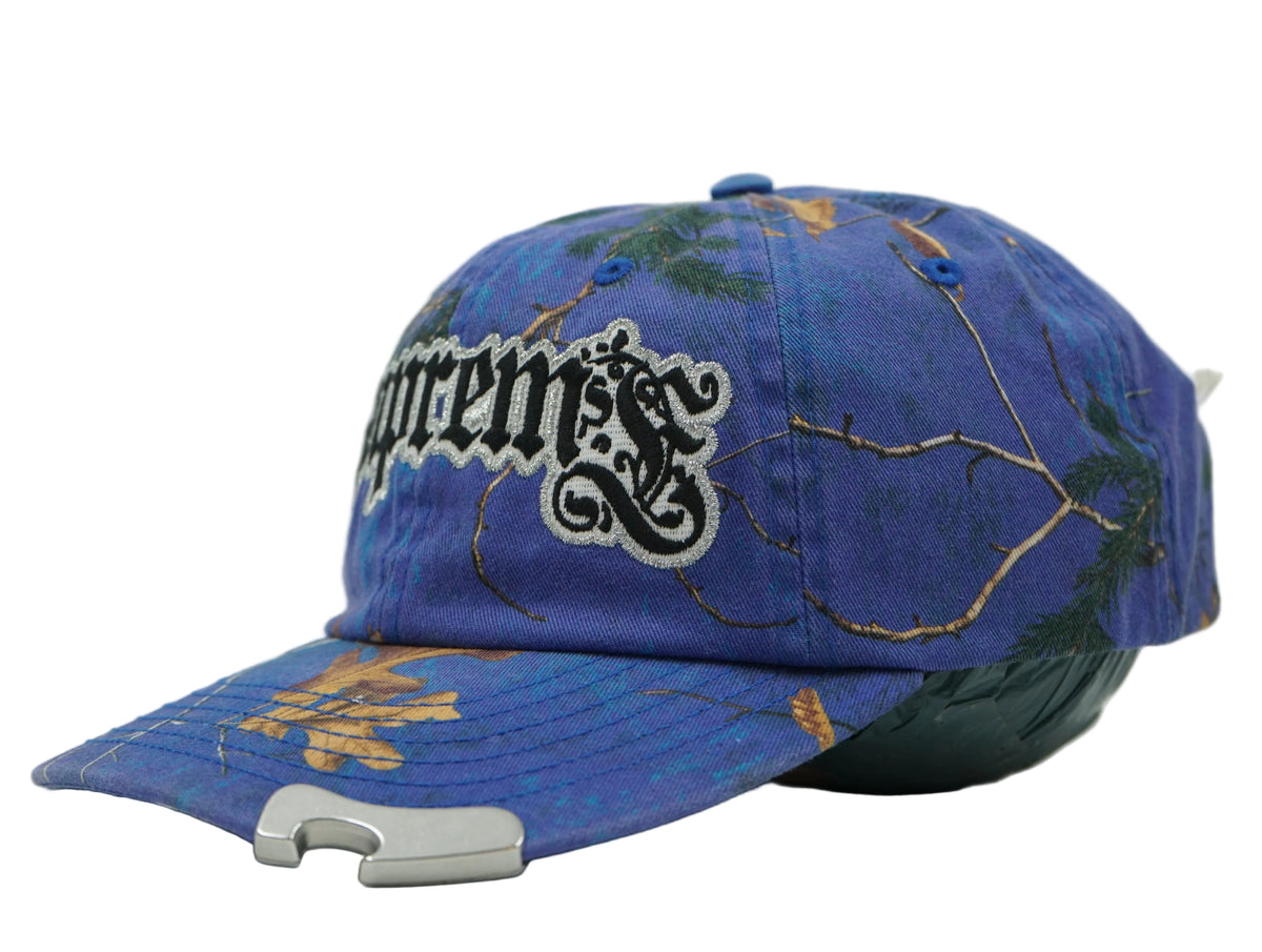 Supreme Bottle Opener 6-Panel cap in blue camo with gothic logo and metal opener on peak, side view
