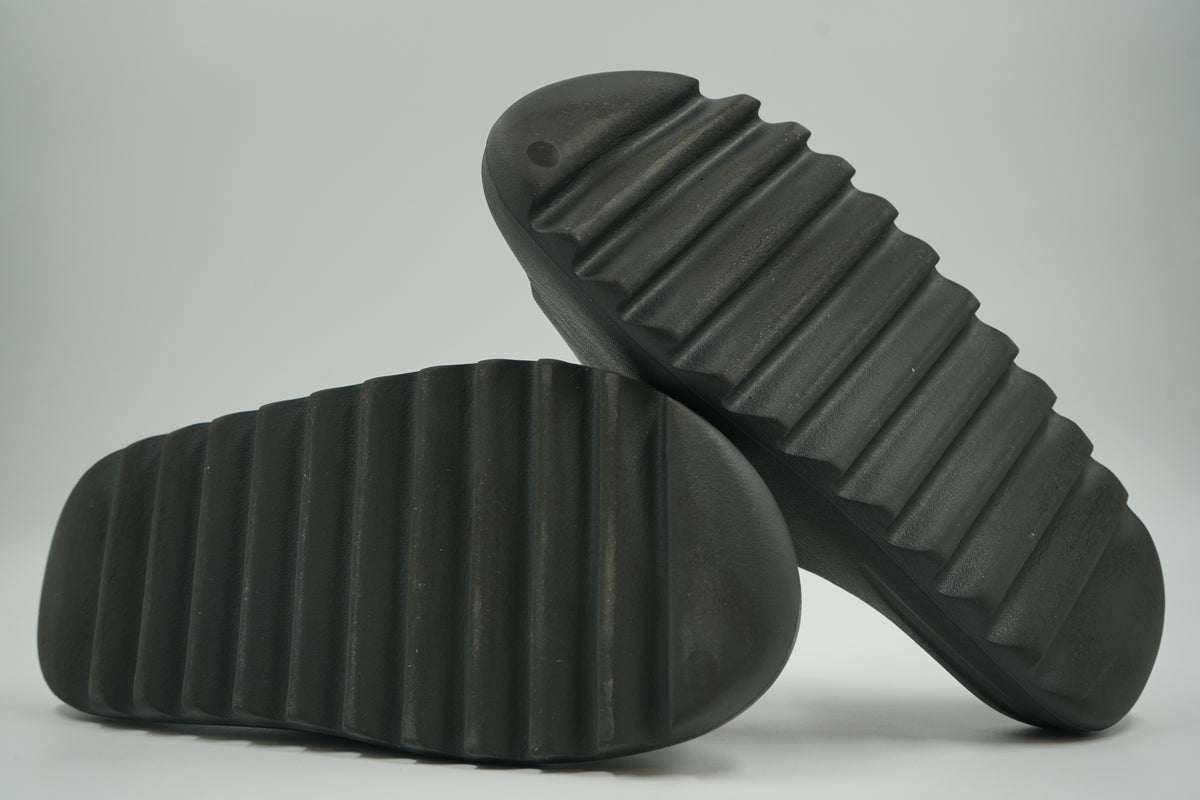 Outsoles of pre-owned adidas Yeezy Slides Onyx HQ6448 with lightly worn ridged tread